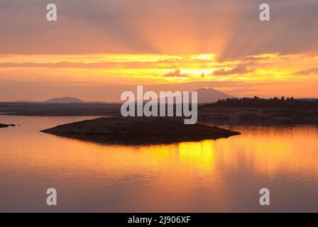 Cielo arancione con riflessi dai raggi del sole nel serbatoio Gabriel y Galan Extremadura Foto Stock