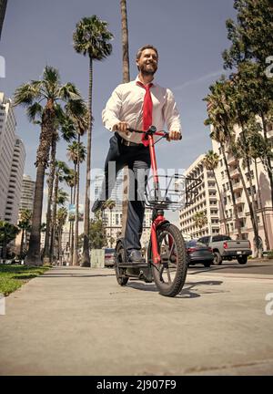 E-sessing lungo. L'uomo felice guida e-scooter su strada. E-sessing. Trasporto elettrico Foto Stock