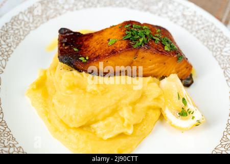 Bistecca di salmone fritta, purè di patate e limone affettato su piatto bianco, closeup. Foto Stock