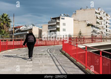 Freattyda, Atene - Grecia - 12 28 2019 turista a piedi su un ponte pedonale rosso al centro di trasporto Olympiakos Foto Stock