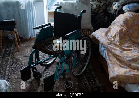 sedia a rotelle vuota in una vecchia casa molto povera Foto Stock