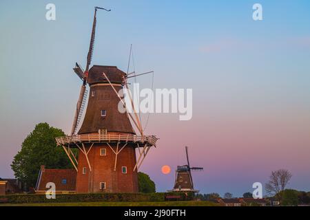 Tramonto e luna con luna piena vicino a Flour Mill 'De Hoop' e 'Zeldenrust' nella città olandese di Dokkum, nella provincia di Frisia nel nord Foto Stock