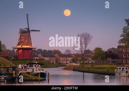 Tramonto e luna piena nei pressi di Flour Mill 'De Hoop' nella città olandese di Dokkum, nella provincia di Frisia nella parte settentrionale della N Foto Stock