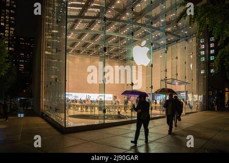 New York, NY, US-Ottobre 26, 2021: Persone con ombrelloni camminano presso Apple computer Store in una notte di pioggia. Foto Stock