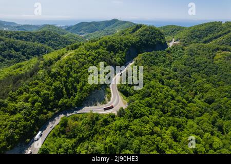 Vista aerea della strada tortuosa dal passo di montagna alto. Ottima gita su strada attraverso i fitti boschi. Vista panoramica degli uccelli. Foto Stock