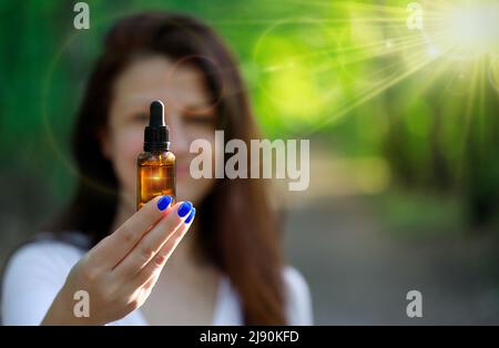 Contagocce cosmetico ambrato nelle mani della donna, unghie blu. Spazio di testo. Foto Stock