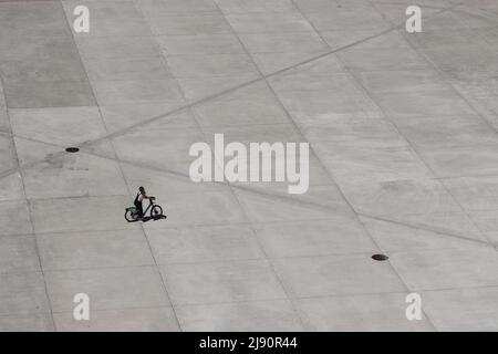 Una ragazza su una bici elettrica a noleggio Gira cerca i suoi amici sul lungomare di Lisbona Foto Stock