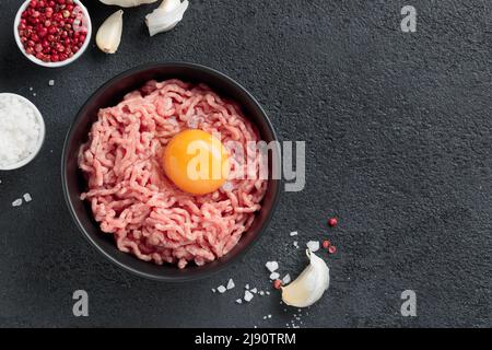 Ingredienti delle cutlet carne di farsa di manzo con uova in un piatto su sfondo nero vista dall'alto Foto Stock