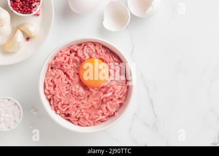 Ingredienti delle cutlet carne di farsa di manzo con uova in un piatto su sfondo bianco vista dall'alto Foto Stock