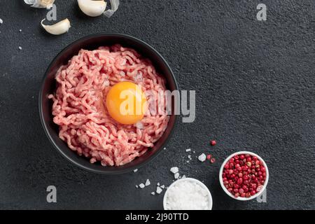 Ingredienti delle cutlet carne di farsa di manzo con uova in un piatto su sfondo nero vista dall'alto Foto Stock