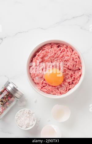 Ingredienti delle cutlet carne di farsa di manzo con uova in un piatto su sfondo bianco vista dall'alto Foto Stock