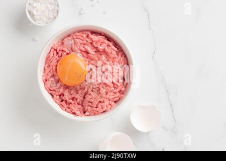 Ingredienti delle cutlet carne di farsa di manzo con uova in un piatto su sfondo bianco vista dall'alto Foto Stock