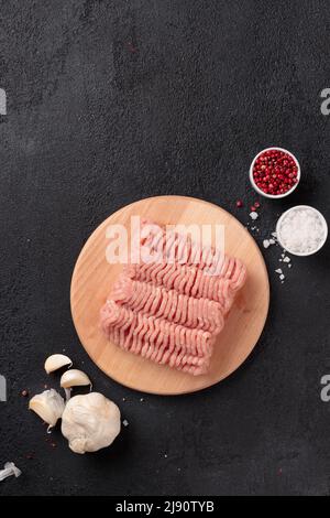 Carne cruda, carne di farsa di pollame su un asse di legno su sfondo nero Foto Stock