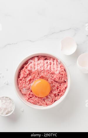 Ingredienti delle cutlet carne di farsa di manzo con uova in un piatto su sfondo bianco vista dall'alto Foto Stock