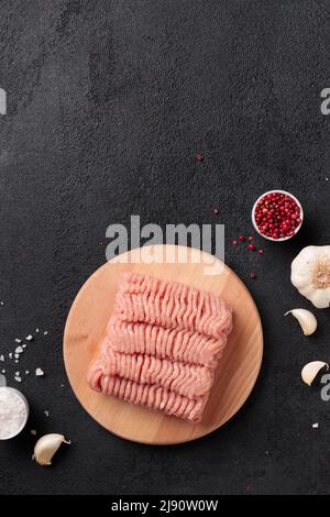 Carne cruda, carne di farsa di pollame su un asse di legno su sfondo nero Foto Stock