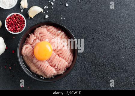 Ingredienti cutlet pollame farce carne con uovo in un piatto su sfondo nero vista dall'alto Foto Stock