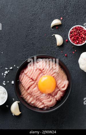 Ingredienti cutlet pollame farce carne con uovo in un piatto su sfondo nero vista dall'alto Foto Stock