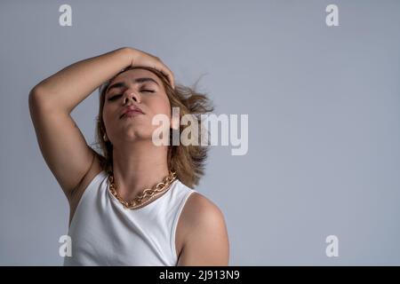 Ritratto di accpetance angrogynous giovane con capelli lunghi e stile fresco con atteggiamento calmo in studio Foto Stock