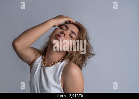 Ritratto di accpetance angrogynous giovane con capelli lunghi e stile fresco con atteggiamento calmo in studio Foto Stock