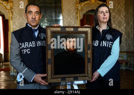 Torino, Italia. 19 maggio 2022. Il dipinto 'Ritratto di un gentleman in un cappellino nero' ('Ritratto di gentiluomo con berretto nero') attribuito a Tiziano (Tiziano Vecellio) è tenuto dai membri dei Carabinieri dell'unità di protezione dei Beni culturali di Torino durante la cerimonia di restituzione allo Stato italiano. L'opera d'arte era scomparsa dal 2003 al 2020 ed è stata rinvenuta dai Carabinieri dell'unità di protezione dei Beni culturali di Torino, il suo valore stimato è di circa 7 milioni di euro. Credit: Nicolò campo/Alamy Live News Foto Stock