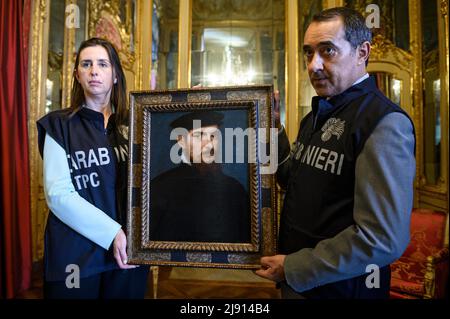 Torino, Italia. 19 maggio 2022. Il dipinto 'Ritratto di un gentleman in un cappellino nero' ('Ritratto di gentiluomo con berretto nero') attribuito a Tiziano (Tiziano Vecellio) è tenuto dai membri dei Carabinieri dell'unità di protezione dei Beni culturali di Torino durante la cerimonia di restituzione allo Stato italiano. L'opera d'arte era scomparsa dal 2003 al 2020 ed è stata rinvenuta dai Carabinieri dell'unità di protezione dei Beni culturali di Torino, il suo valore stimato è di circa 7 milioni di euro. Credit: Nicolò campo/Alamy Live News Foto Stock