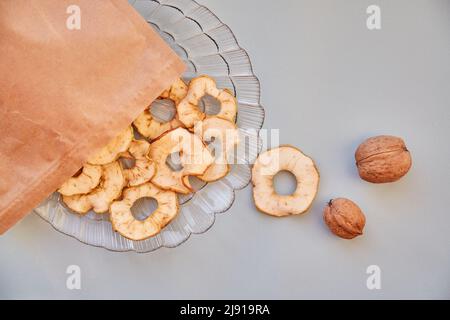 Sacchetto di carta con patatine e noci di mela a fette essiccate - spuntini sani sul piatto. Vista dall'alto. Nutrizione adeguata, concetto di cibo sano. Foto di alta qualità Foto Stock