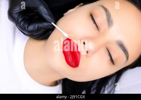 Modello prima della procedura di make-up permanente con labbra rosse dipinte Foto Stock