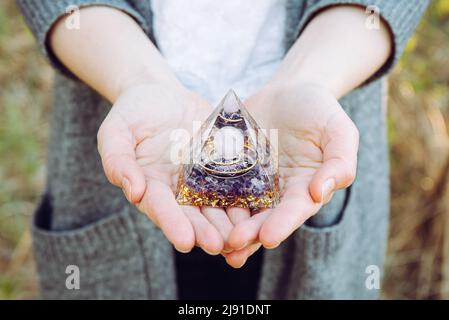 Vista ravvicinata delle mani della donna che tengono e utilizzano Orgonite o Orgone Pyramid. Convertire l'energia negativa in energia positiva ed avere poteri curativi. Foto Stock