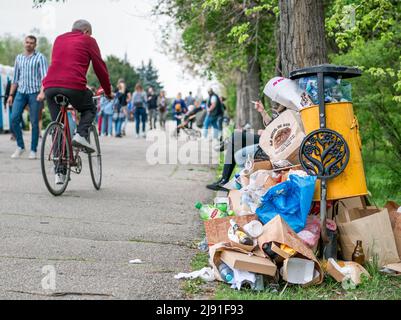Bucarest, Romania - 04.15.2022: Cestino pieno di rifiuti. Spazzatura traboccante con molte persone intorno al parco di re Mihai i (Herestrau). Ambiente Foto Stock