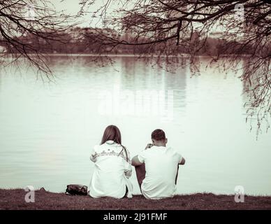 Foto monocromatica vintage con una coppia seduta sul bordo di un lago Foto Stock