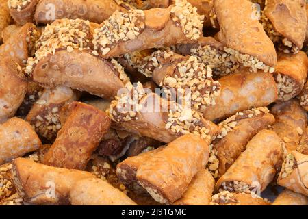 Tipico dessert italiano chiamato cannolo con ripieno di cioccolato e nocciole tritate in vendita presso pasticcerie Foto Stock