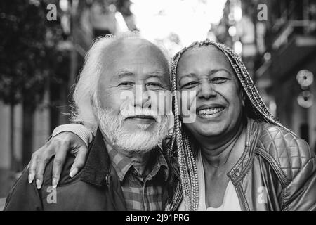 Coppia anziana multietnica che guarda la macchina fotografica outdoor - Viaggi, anziani concetto - Focus on african woman face - montaggio in bianco e nero Foto Stock