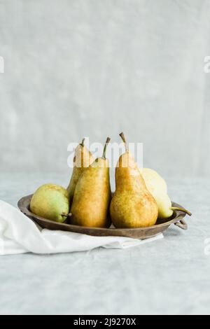 Pere su un tavolo in una ciotola d'argento antico Foto Stock