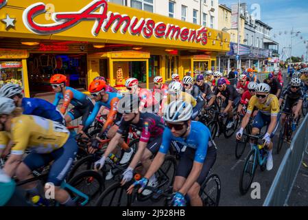 Clacton on Sea, Essex, Regno Unito. 19th maggio 2022. La Sportsbreaks Tour Series 2022 ha raggiunto la città balneare di Clacton on Sea, che ospita una gara maschile seguita da una gara femminile. Ogni gara dura un'ora più cinque giri intorno al circuito lungo 1,4km attraverso la città nel tardo pomeriggio e la sera, con l'inizio e la fine sul lungomare Marine Parade East. Sia le gare maschili che quelle femminili erano composte da 13 squadre, ciascuna delle quali contava un massimo di cinque piloti, il che ha reso possibile un ampio campo di piloti intorno al campo stretto. La gara maschile è stata vinta da Matt Bostock. Ciclisti che passano i divertimenti Foto Stock