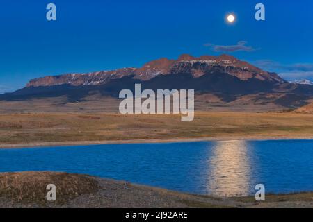 luna piena ambientazione dietro cresta seghdente e un laghetto di prateria lungo il fronte roccioso di montagna vicino choteau, montana Foto Stock