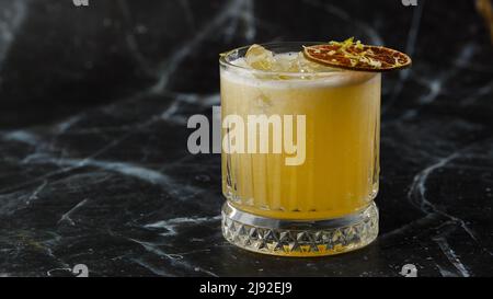 Mix di frutta con mezcal e calce secca su sfondo di marmo nero. Cocktail dai colori caldi. Cocktail mezcal Foto Stock
