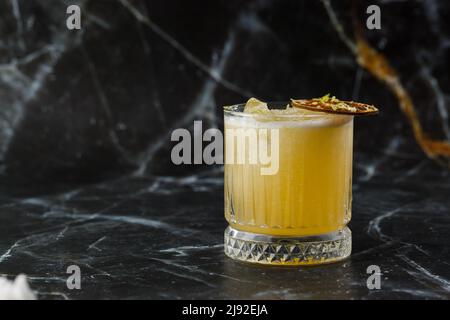 Mix di frutta con mezcal e calce secca su sfondo di marmo nero. Cocktail dai colori caldi. Cocktail mezcal Foto Stock