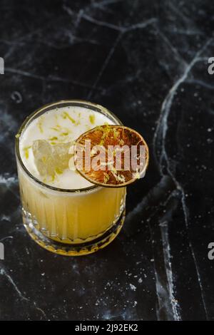 Mix di frutta con mezcal e calce secca su sfondo di marmo nero. Cocktail dai colori caldi. Cocktail mezcal Foto Stock