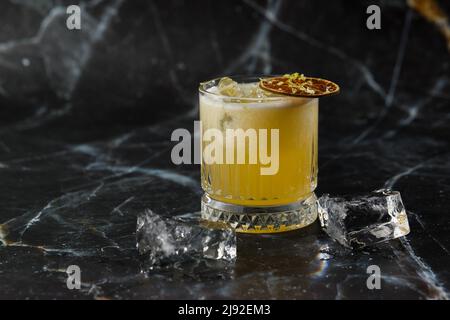 Mix di frutta con mezcal e calce secca su sfondo di marmo nero. Cocktail dai colori caldi. Cocktail mezcal Foto Stock