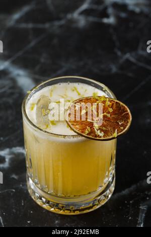 Mix di frutta con mezcal e calce secca su sfondo di marmo nero. Cocktail dai colori caldi. Cocktail mezcal Foto Stock