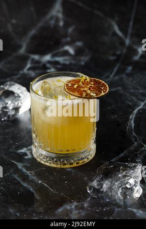 Mix di frutta con mezcal e calce secca su sfondo di marmo nero. Cocktail dai colori caldi. Cocktail mezcal Foto Stock