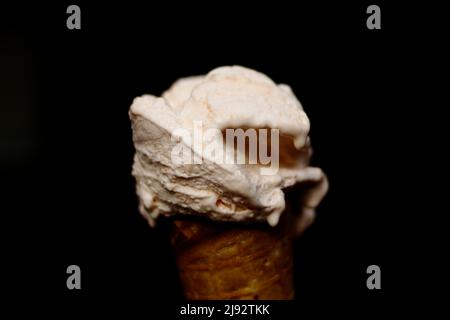 Gelato all'arancia in un cono di cialda su sfondo nero - gelato italiano Foto Stock