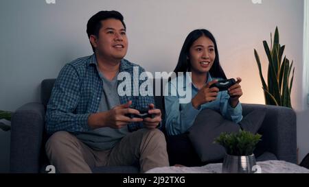 Le coppie asiatiche stanno divertendosi a giocare nel loro soggiorno di notte. Foto Stock