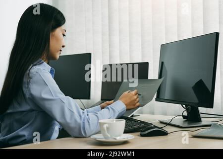 Donna asiatica sviluppatori di software seduti di fronte ai computer guardando i codici computer sullo schermo. Foto Stock