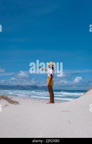 Cape Nature Walker Bay spiaggia vicino Hermanus Western Cape Sud Africa. Spiaggia bianca e cielo blu con nuvole, dune di sabbia alla spiaggia in Sud Africa, donna che cammina a spiaggia bianca Foto Stock