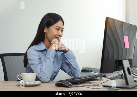 Donna asiatica sviluppatori di software seduti di fronte ai computer guardando i codici computer sullo schermo. Foto Stock