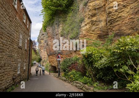 Persone che camminano vicino cadere rocce segno e rete di sicurezza metallo che copre le rocce vicino sentiero a Knaresborough, Harrogate, North Yorkshire Foto Stock