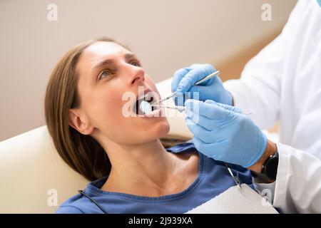 Dentista maschio trattando i denti di giovane donna incinta paziente sdraiato in clinica Foto Stock