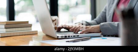 Business analista concetto la donna ufficiale digitando informazioni finanziarie sul computer portatile. Foto Stock