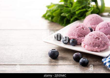 Misurini per gelato al mirtillo su tavola di legno Foto Stock